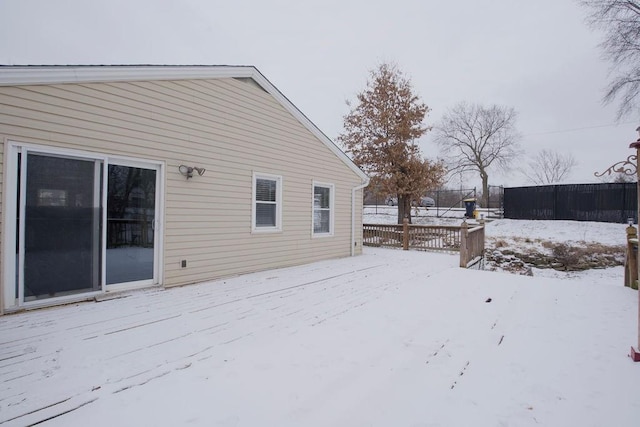 snow covered house featuring fence