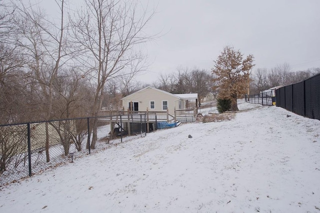 snow covered back of property with fence and a deck