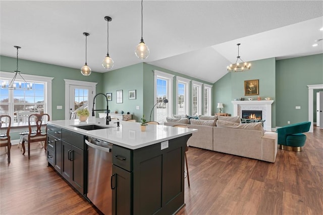 kitchen with a sink, a notable chandelier, stainless steel dishwasher, and a warm lit fireplace