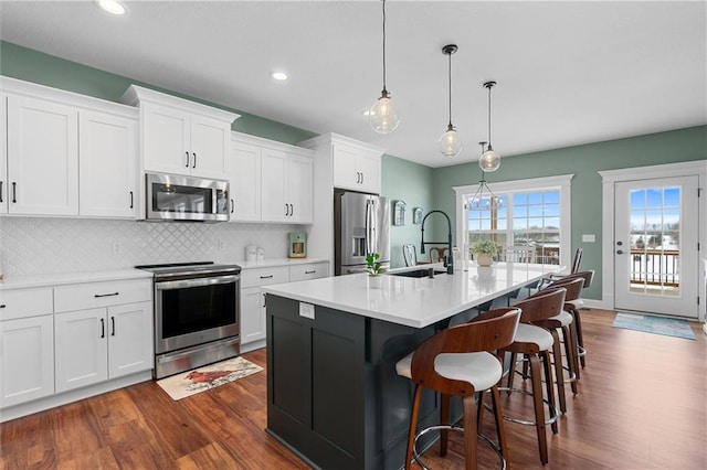 kitchen featuring dark wood-style flooring, a sink, decorative backsplash, stainless steel appliances, and white cabinets