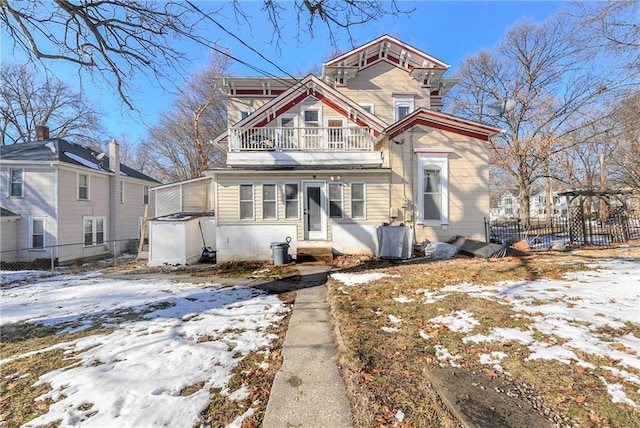 view of front of property with fence and a balcony