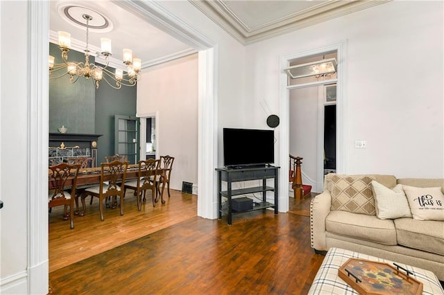 living room with dark wood-style floors, ornamental molding, and a chandelier