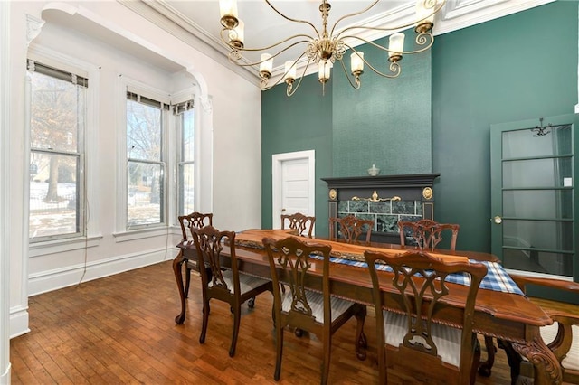 dining area with a chandelier, arched walkways, a fireplace, ornamental molding, and dark wood finished floors