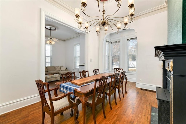 dining area with baseboards, ornamental molding, hardwood / wood-style floors, and ceiling fan with notable chandelier