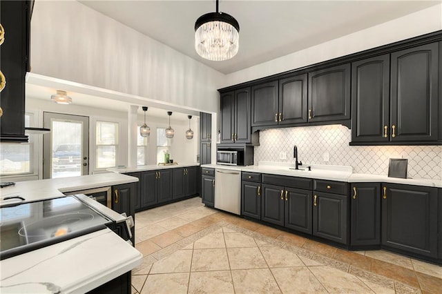 kitchen with decorative backsplash, light countertops, stainless steel dishwasher, and decorative light fixtures