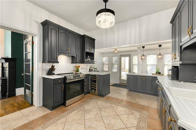 kitchen with light countertops, hanging light fixtures, backsplash, and stainless steel electric range