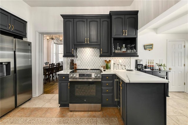 kitchen with a peninsula, backsplash, stainless steel appliances, and light countertops