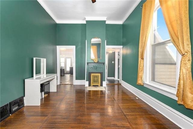 living area with ornamental molding, dark wood finished floors, baseboards, and a ceiling fan