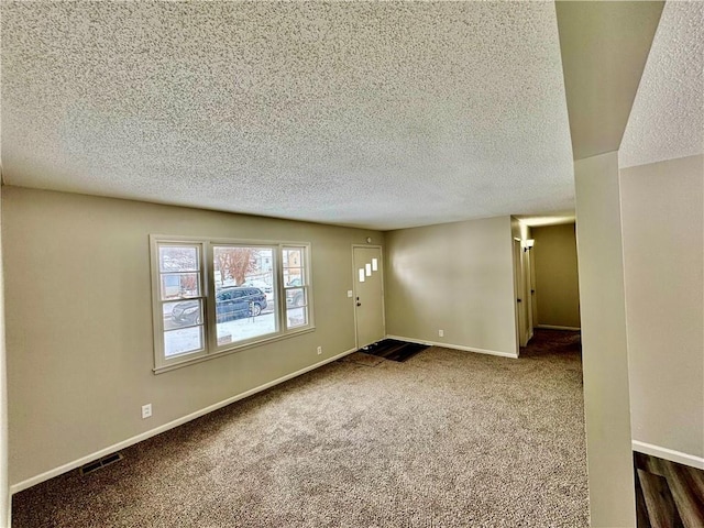 empty room featuring visible vents, baseboards, and dark carpet