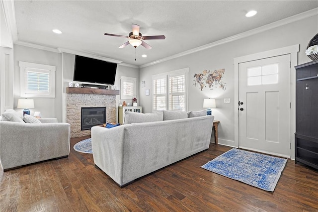 living room with a ceiling fan, a fireplace, ornamental molding, and dark wood-style flooring