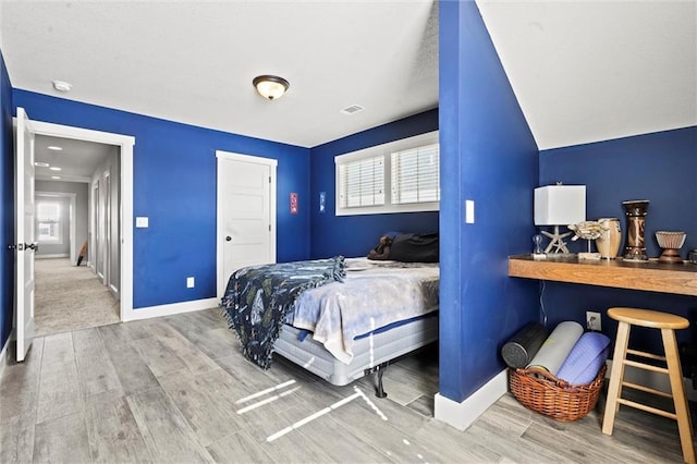 bedroom with visible vents, baseboards, and wood finished floors