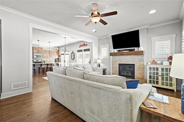 9011 NE 79th St, Kansas City, MO 64158 - living area featuring visible vents, ornamental molding, ceiling fan, a fireplace, and dark wood-type flooring