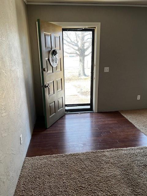 entryway with ornamental molding and dark wood-type flooring