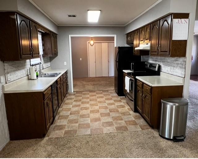 kitchen featuring sink, stainless steel electric range, backsplash, dark brown cabinetry, and light colored carpet