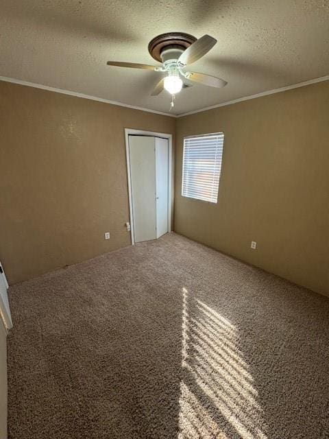 unfurnished bedroom featuring carpet floors, ornamental molding, ceiling fan, a textured ceiling, and a closet