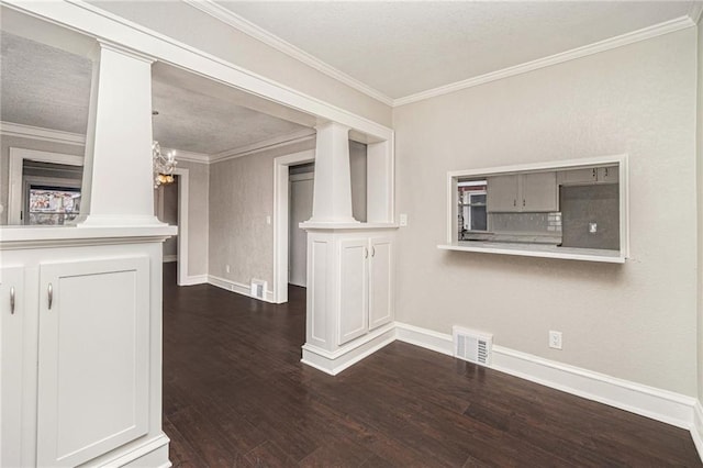 unfurnished living room with a notable chandelier, decorative columns, crown molding, and dark hardwood / wood-style floors