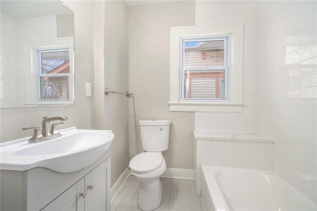 bathroom with toilet, vanity, and a bathtub