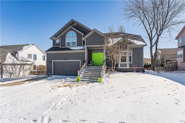 view of front of home with an attached garage, fence, and stucco siding