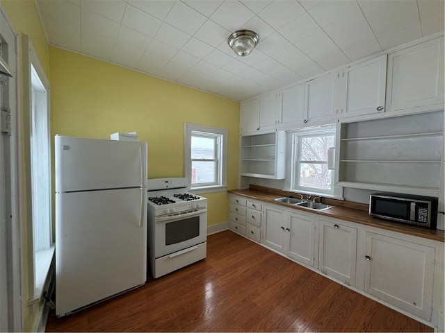 kitchen featuring white appliances, plenty of natural light, wooden counters, and white cabinets