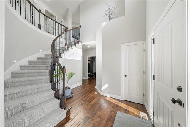 foyer entrance with dark wood-type flooring and a towering ceiling