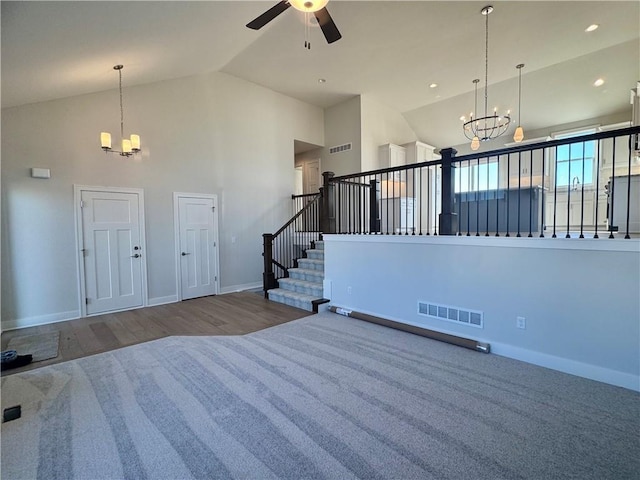 foyer with ceiling fan with notable chandelier, high vaulted ceiling, and hardwood / wood-style floors