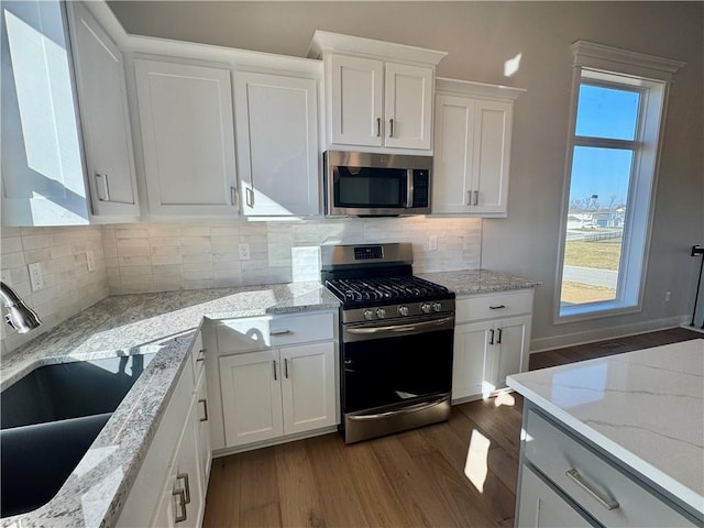 kitchen featuring stainless steel appliances, sink, white cabinets, and light stone counters