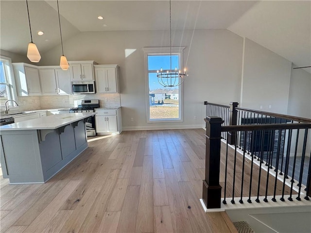 kitchen with a kitchen island, decorative light fixtures, white cabinets, stainless steel appliances, and an inviting chandelier