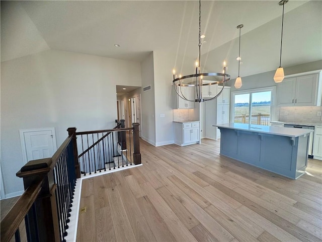 kitchen with pendant lighting, a center island, tasteful backsplash, light hardwood / wood-style floors, and white cabinets