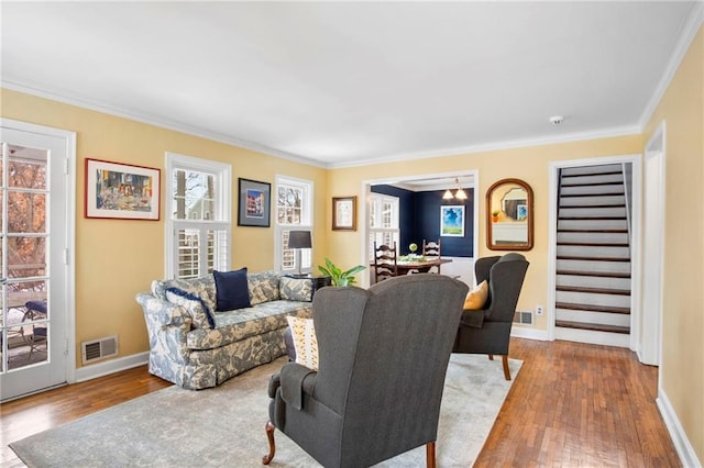 living room with a notable chandelier, crown molding, and light wood-type flooring