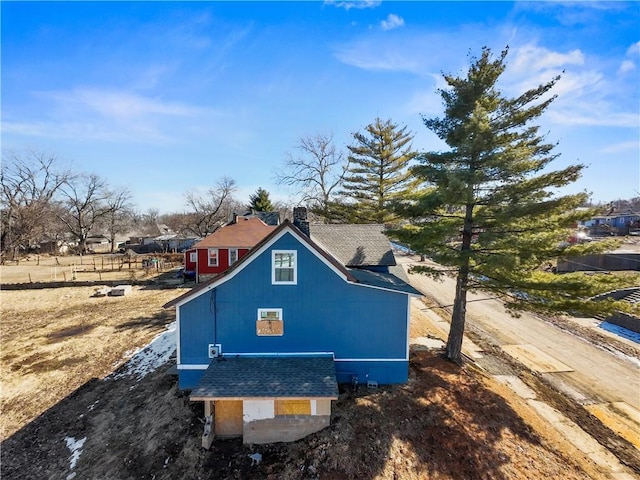 view of home's exterior with a chimney and roof with shingles