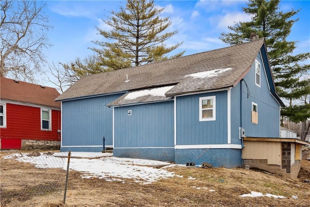 rear view of house featuring fence and roof with shingles