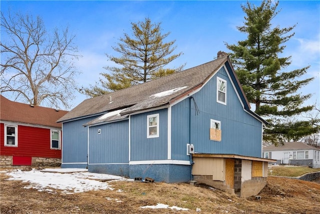 view of side of home with roof with shingles and a chimney