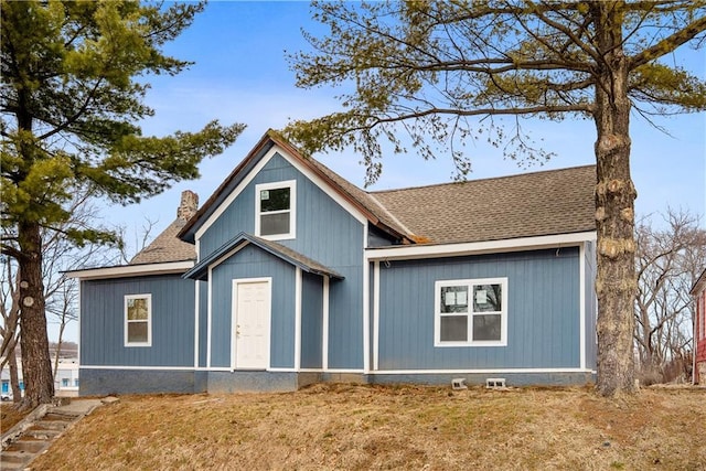 view of front of property featuring a shingled roof, a chimney, and a front lawn