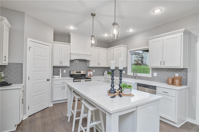 kitchen featuring hanging light fixtures, stainless steel appliances, white cabinets, and a kitchen island