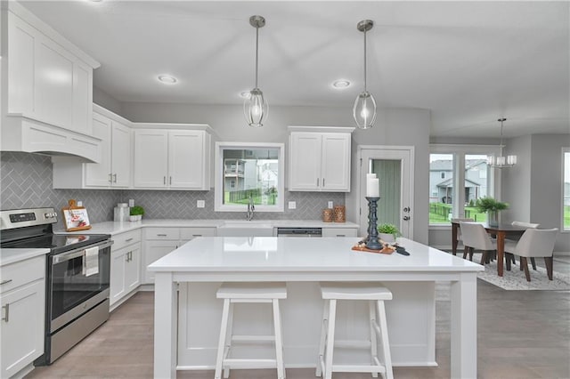 kitchen featuring white cabinetry, stainless steel electric range oven, and hanging light fixtures