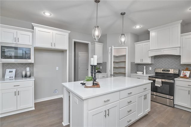 kitchen featuring a kitchen island, appliances with stainless steel finishes, pendant lighting, white cabinets, and dark hardwood / wood-style flooring