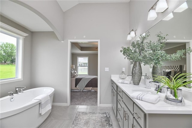 bathroom with vaulted ceiling, vanity, a bathing tub, and tile patterned flooring