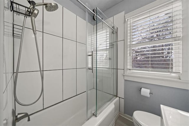 full bath featuring toilet, baseboards, and bath / shower combo with glass door