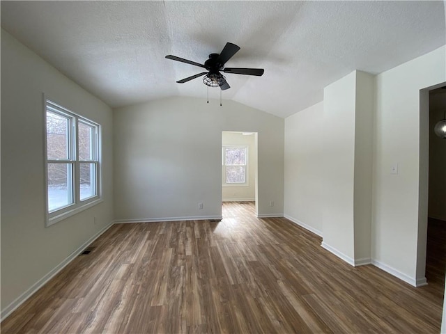 empty room with dark hardwood / wood-style flooring, ceiling fan, lofted ceiling, and a textured ceiling