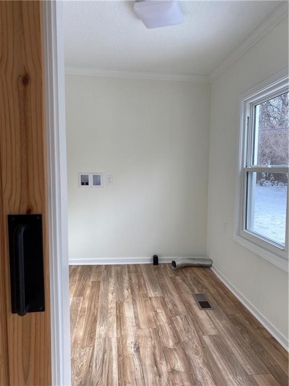 clothes washing area with wood-type flooring, ornamental molding, and washer hookup