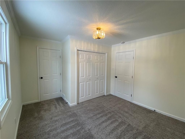 unfurnished bedroom featuring dark carpet, crown molding, multiple windows, and a closet