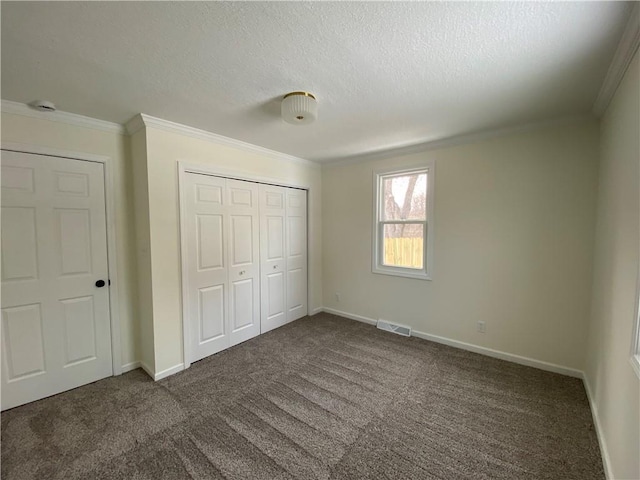 unfurnished bedroom featuring dark colored carpet, a textured ceiling, and crown molding