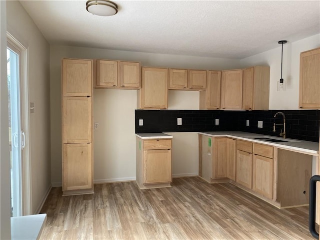 kitchen with sink, pendant lighting, light brown cabinets, and light hardwood / wood-style floors