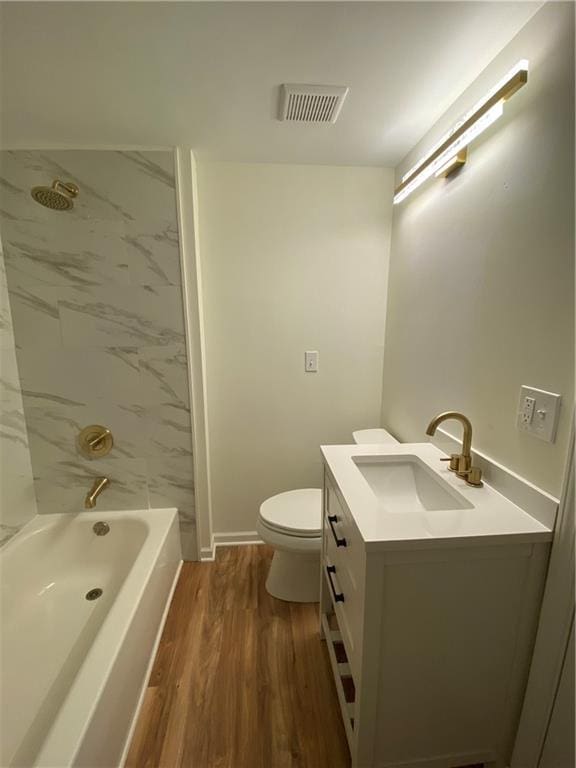 full bathroom with tiled shower / bath combo, vanity, hardwood / wood-style floors, and toilet