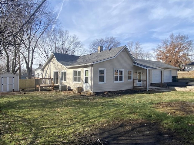 back of property with a yard, central AC, and a storage unit