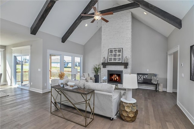 living room featuring a large fireplace, dark wood finished floors, beam ceiling, and baseboards