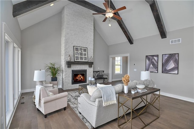 living room with baseboards, visible vents, wood finished floors, beamed ceiling, and a fireplace