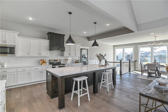 kitchen with white cabinets, appliances with stainless steel finishes, a breakfast bar, and wood finished floors