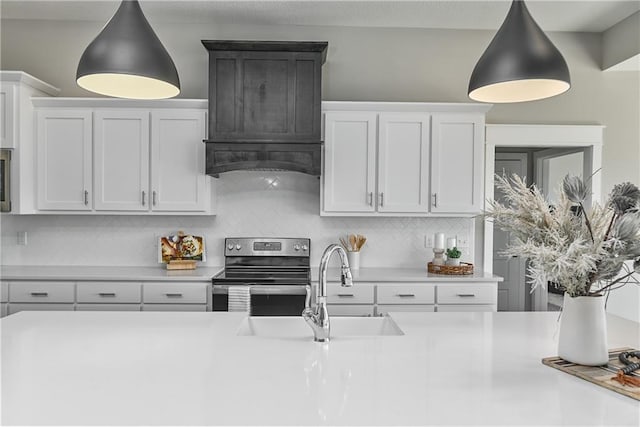 kitchen with stainless steel electric range oven, light countertops, tasteful backsplash, and a sink