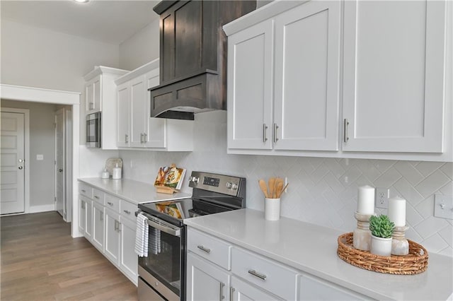 kitchen with tasteful backsplash, appliances with stainless steel finishes, light countertops, light wood-style floors, and white cabinetry